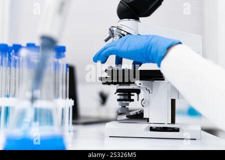 Eine Nahaufnahme einer Laborszene, die einen Forscher oder Mediziner mit einem Mikroskop zeigt, wobei Präzision und wissenschaftliche Untersuchung hervorgehoben werden Stockfoto