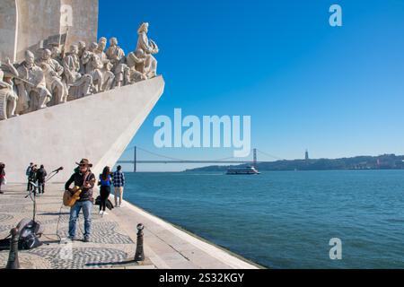 Lissabon, Portugal - Ein Straßenkünstler mit Gitarre und Mikrofon unterhält eine Menge Touristen im Padrão dos Descobrimentos in Belém. Stockfoto