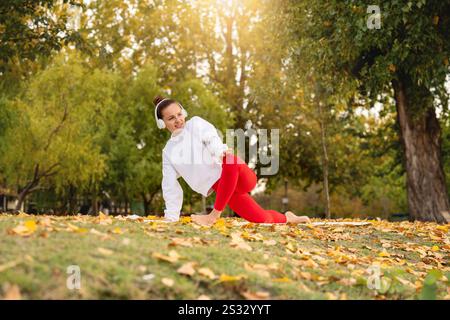 Moderne Frau mit schnurlosen Kopfhörern und Sportkleidung, die im Stadtpark im Freien Sport treibt. Stockfoto