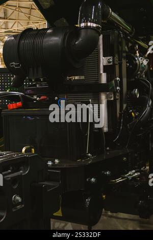 Eine Nahaufnahme eines modernen Traktors mit geöffneter Motorhaube, der den leistungsstarken Motor und die komplizierte Mechanik zeigt Stockfoto