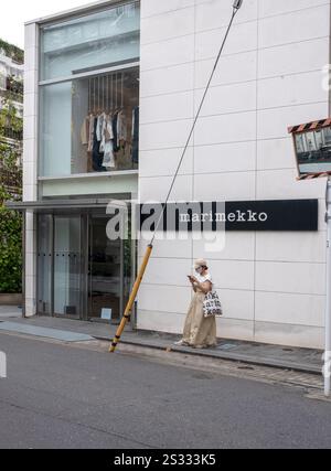 Junge trendige Frau, die vor dem Marimekko Store in Omotesando Tokio, Japan, steht Stockfoto