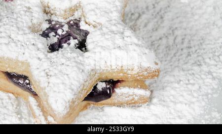 Festliche, sternförmige Kekse gefüllt mit Marmelade und mit Puderzucker überzogen schaffen ein süßes Urlaubsvergnügen, perfekt zum Teilen. Stockfoto