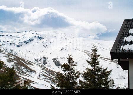 Eine atemberaubend atemberaubende, schneebedeckte Berglandschaft mit immergrünen Kiefern und dramatischen, wirbelnden Wolken Stockfoto