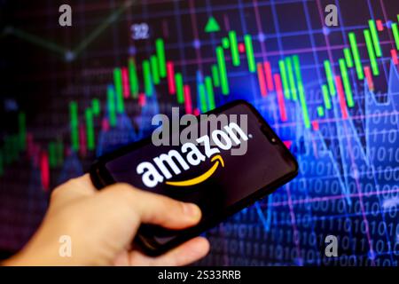 In dieser Fotoabbildung wird das Amazon-Logo, eine Online-eCommerce-Plattform, auf einem Smartphone-Bildschirm vor einem Computerbildschirm mit einem Bild angezeigt Stockfoto