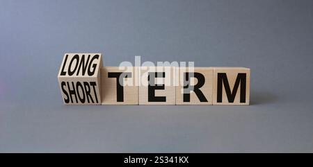 Symbol für Langzeit vs. Kurzzeit. Gedrehte Holzwürfel mit Wörtern für lange und kurze Zeit. Schöner grauer Hintergrund. Geschäftskonzept. Kopierbereich. Stockfoto