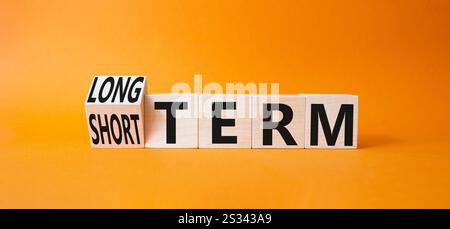 Symbol für Langzeit vs. Kurzzeit. Gedrehte Holzwürfel mit Wörtern für lange und kurze Zeit. Wunderschöner orangefarbener Hintergrund. Geschäftskonzept. Kopierbereich. Stockfoto