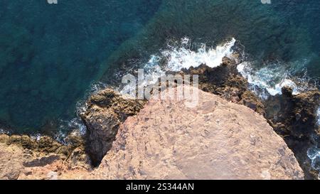 Blick aus der Vogelperspektive auf einen ruhigen Strand mit den Menschen, die den weichen Sand und das flache türkisfarbene Wasser genießen Stockfoto