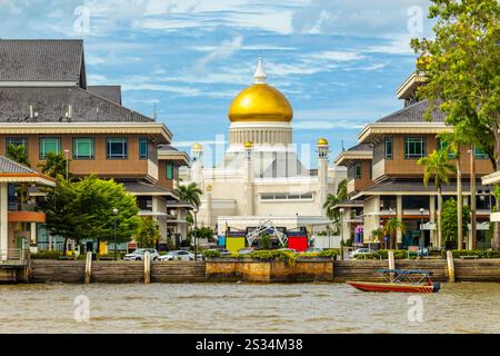 Promenade Stadtstraße mit Flussufer und Boot im Vordergrund, mit goldenen Kuppeln und Minaretten der Omar Ali Saifuddien Moschee, Bandar Seri Begawan, Borneo, Stockfoto
