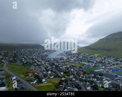 Wunderschöner Blick aus der Vogelperspektive auf die Stadt Klaksvik auf den Fareo-Inseln mit ihren bunten Häusern und dem atemberaubenden Kanal und Blick auf den majestätischen Kunoy Park Stockfoto