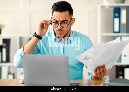 Betonte arabischen Mitarbeiter mit Laptop und Dokumente Probleme mit der Arbeit, Fehler in Geschäftsprojekt im Büro Stockfoto