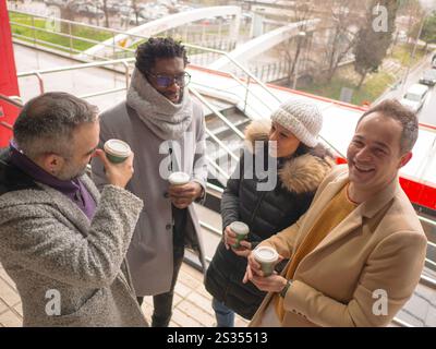 Vier Büroangestellte machen eine Kaffeepause in einem geschäftigen Geschäftsviertel. Ein Schwarzer Mann, eine Frau und zwei hispanische Individuen stehen zusammen. Nur o Stockfoto