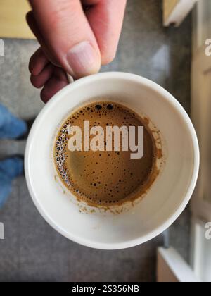 Eine männliche Hand, die eine Tasse Kaffee von oben hält. Stockfoto