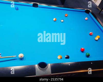 Billard-Queue in den Händen eines Spielers, der während des Spiels weißen Ball schlägt. Stockfoto