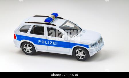 Weißes und blaues deutsches Polizeispielzeugauto parkt auf einem nahtlosen hellen Hintergrund Stockfoto