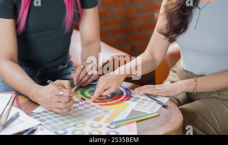 LGBTQ+ Transgender Mann schöner authentischer Spezialist mit rosafarbenen Haaren und nicht-binären Trans, die zusammen arbeiten Design im kreativen Arbeitsplatzteam W Stockfoto