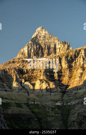 Der Gipfel des Thunderbird Mountain leuchtet im warmen Morgenlicht vor Einem klaren blauen Himmel im Glacier National Park Stockfoto