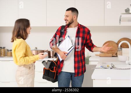 Junge Frau mit Klempner in der Nähe des Waschbeckens in der Küche Stockfoto