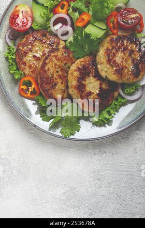 Gebratene Hähnchenkoteletts, gehacktes Hähnchen, mit Gemüse, auf Grau, mit Gemüsesalat, Aussicht von oben, hausgemacht, keine Leute Stockfoto