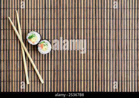 Sushi rollen und liegen auf einem hölzernen Eßstäbchen Bambus Stroh serwing Mat. Traditionelle asiatische Lebensmittel. Ansicht von oben. Flach Minimalismus shot mit kopieren. Stockfoto