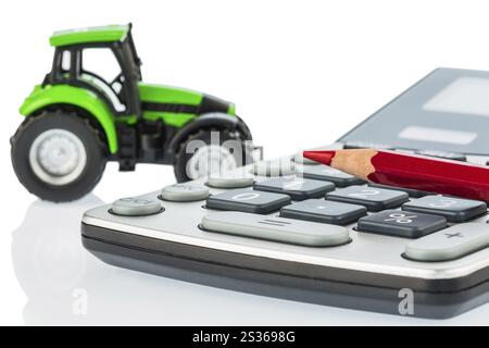 Ein Traktor und ein roter Stift auf einem Rechner. Kosten für Benzin, Verschleiß und Versicherung. Kosten und Subventionen in der Landwirtschaft Stockfoto