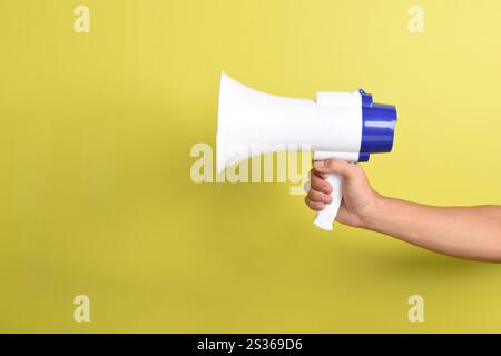 Megaphon in der Hand des Menschen isoliert auf gelbem Hintergrund. Konzept der Einstellung, Werbung für etwas. Banner. Kopierbereich Stockfoto