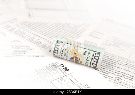 1120 U.S. Corporation Einkommensteuererklärung Form mit der Rolle des amerikanischen Dollar Banknoten hautnah. Konzept der Steuerperiode in den Vereinigten Staaten Stockfoto