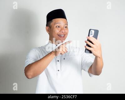 Porträt eines muslimisch-asiatischen Mannes Videoanrufe mit fröhlichem und aufgeregtem Ausdruck. Mann, der die Online-App für Konferenzen zu Hause nutzt. Stockfoto