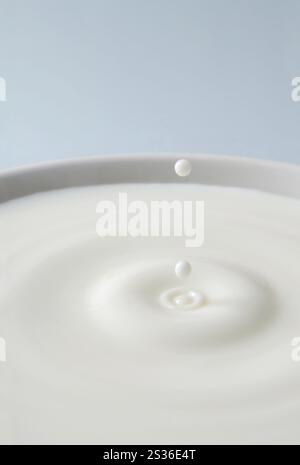 Weißer Tropfen Milch künstlerische Nahaufnahme über blauem Hintergrund Stockfoto