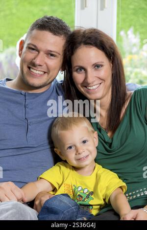 Eine junge Familie sitzt auf einer Couch Austria Stockfoto