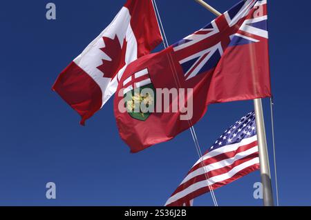 Flaggen von Ontario Kanada und den Vereinigten Staaten fliegen im Wind über blauem Himmel Stockfoto