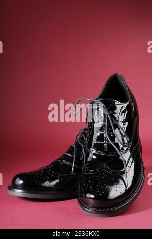 Nahaufnahme eines Paar stilvoller schwarzer Damenschuhe auf rotem Hintergrund Stockfoto