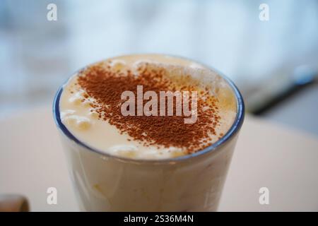Cappuccino mit Kakaopulver in einem Glas auf dem Tisch Stockfoto
