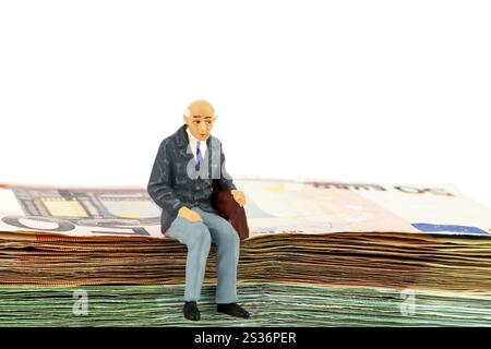 Symbolisches Foto für Ruhestand und Alterssicherung, Figur eines alten Mannes, der auf einem Banknotenstapel sitzt Österreich Stockfoto