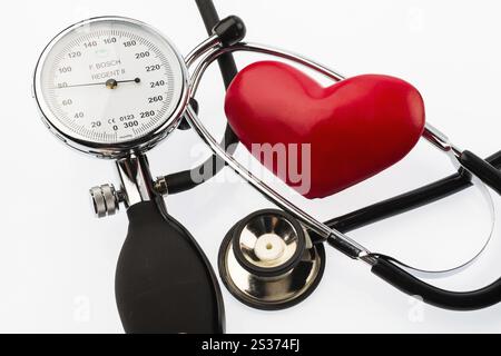 Ein Sphygmomanometer, ein Herz und ein Stethoskop liegen auf weißem Hintergrund Österreich Stockfoto