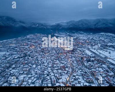 Blick auf eine schneebedeckte Stadt Bansko, eingebettet in Pirin Berge, mit Straßenlaternen, die die Landschaft erleuchten. Bulgarien Stockfoto