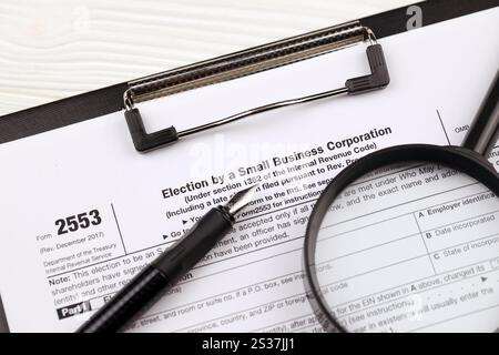 IRS Form 2553 Wahl durch eine Small Business Corporation Steuerleerstelle auf A4-Tablet liegt auf dem Bürotisch mit Stift und Lupe in Nahaufnahme Stockfoto