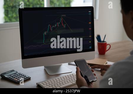 Geschäftsmann Online-Händler mit Computer und Telefon über dynamische Börsen Stockfoto