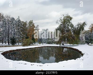 Erste Herbst plötzliche Schnee im Stadtpark und kleinen Teich Stockfoto