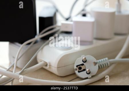 Überlastete Stromversorgungsplatinen. Steckdosenleisten mit verschiedenen Steckern auf weißem Boden. Konzept der Gefahr Gefahr Überlaststrom elektrisch. Stockfoto