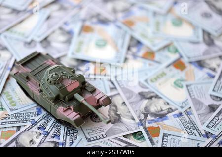 Spielzeugtank auf US-Dollar-Banknoten aus nächster Nähe. Das Konzept der Kriegskosten, der Militärausgaben und der Wirtschaftskrise Stockfoto