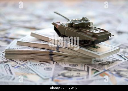 Spielzeugtank auf US-Dollar-Banknoten aus nächster Nähe. Das Konzept der Kriegskosten, der Militärausgaben und der Wirtschaftskrise Stockfoto