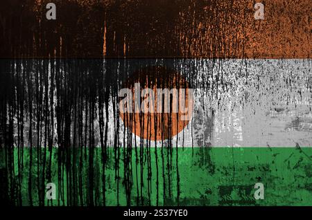 Niger-Flagge in Malfarben auf alten und schmutzigen Ölfasswänden in Nahaufnahme dargestellt. Strukturiertes Banner auf rauem Hintergrund. Niger-Flagge in Farbe dargestellt Stockfoto