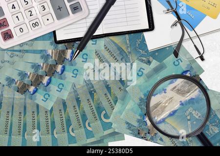 5 kanadische Dollarscheine und Taschenrechner mit Brille und Stift. Steuerzahlungssaisonkonzept oder Investitionslösungen. Job mit hohem Gehalt wird gesucht Stockfoto