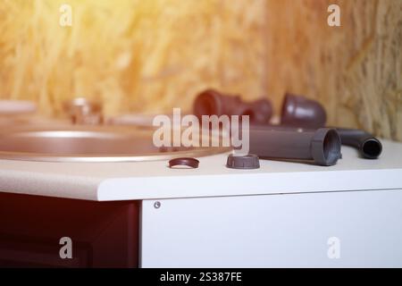 Klempner Werkzeuge und Wasserhahn bereit für die Installation in der Nähe des Waschbeckens auf der Arbeitsplatte in der Küche. Anschlüsse für die Installation des Wasserhahns für den Stockfoto