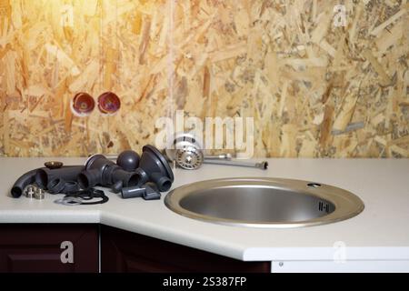 Klempner Werkzeuge und Wasserhahn bereit für die Installation in der Nähe des Waschbeckens auf der Arbeitsplatte in der Küche. Anschlüsse für die Installation des Wasserhahns für den Stockfoto