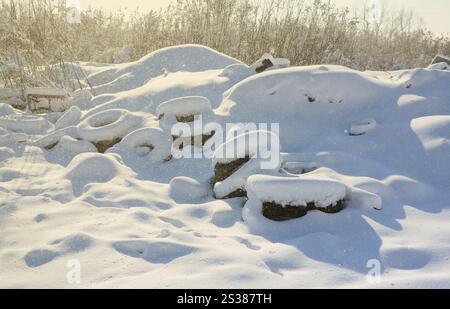 Gebrauchte und entsorgte Autoreifen liegen am Straßenrand und sind mit einer dicken Schneeschicht bedeckt Stockfoto