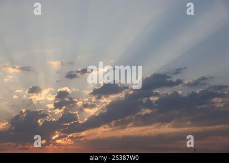Wunderschöner Sonnenaufgang mit warmem orangenem Sonnenlicht und Sonnenstrahlen durch den bewölkten blauen Himmel. Wunderschöner Sonnenaufgang mit warmem orangenem Sonnenlicht und Sonnenstrahlen durch den blauen Himmel Stockfoto