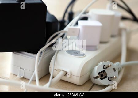 Überlastete Stromversorgungsplatinen. Steckdosenleisten mit verschiedenen Steckern auf weißem Boden. Konzept der Gefahr Gefahr Überlaststrom elektrisch. Stockfoto