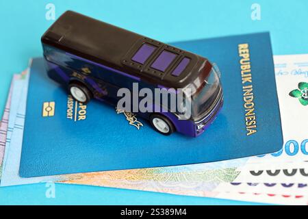 Blauer Indonesien-Pass mit Geld und Spielzeugbus auf blauem Hintergrund Nahaufnahme. Tourismus und Reisekonzept. Pass der Blauen Republik Indonesien Stockfoto