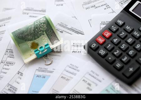 Polnisches Zloty-Geld PLN, Taschenrechner und Stift auf einer großen Menge polnischer PIT-, CIT- und Mehrwertsteuerformulare aus nächster Nähe. Buchhaltung, Bürokratie und Steuerzahler Stockfoto